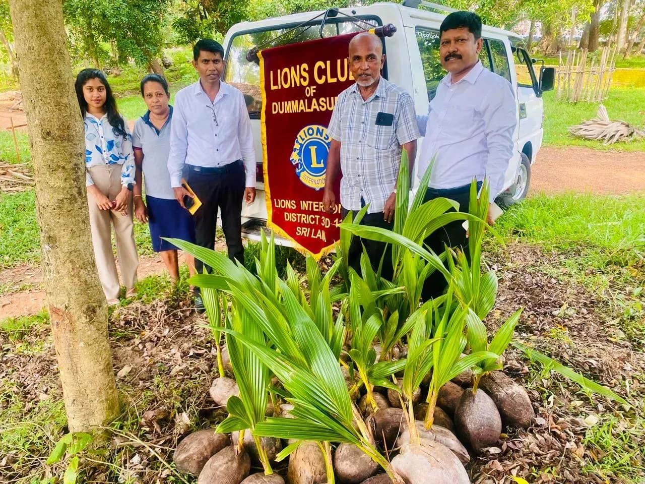 Club members beside coconut saplings and the Dummalasuriya club banner.